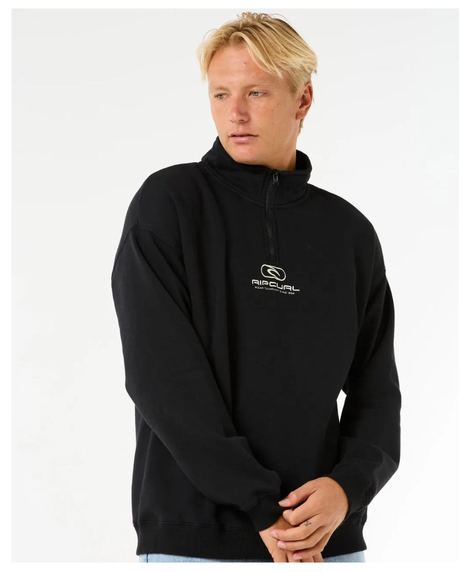 Front view of model wearing Rip Curl Pill Icon 1/4 Zip Crew in black with embroidered logo.