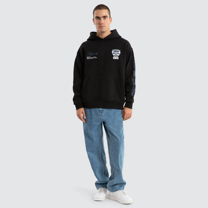 Man wearing a black hoodie with logos and blue jeans on a white background