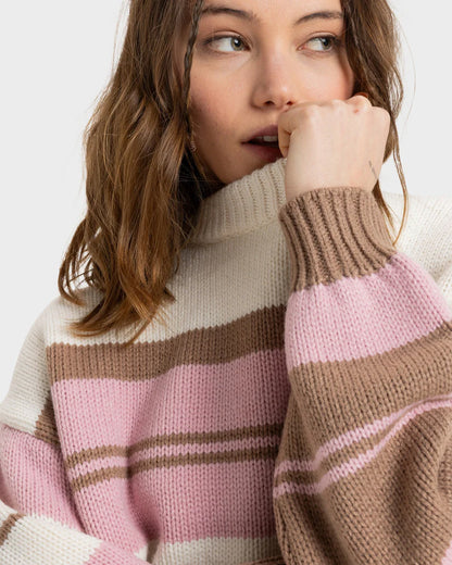 Woman wearing the Roxy Love Again Knit Jumper with beige, pink, and brown horizontal stripes, resting her hand near her face and looking off-camera.